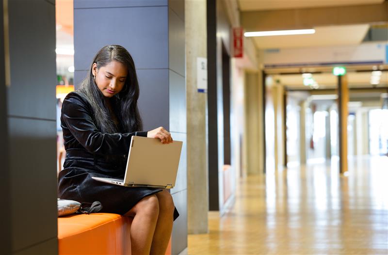 Een vrouw zit met haar laptop op de bank